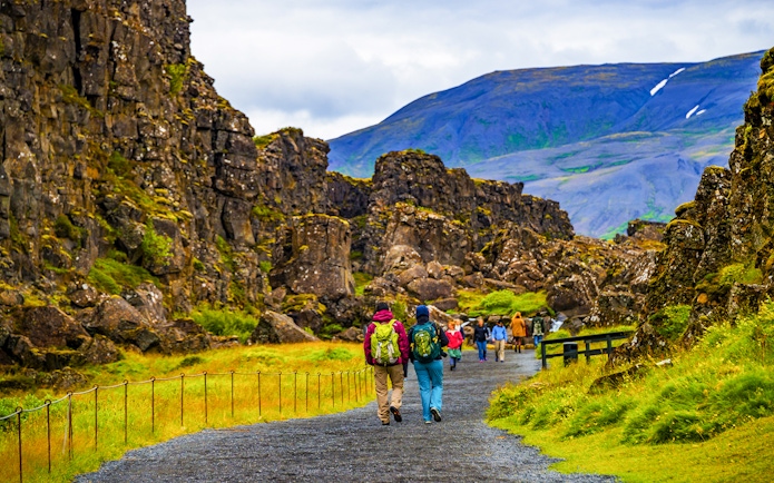Tour group walking through Thingvellir National Park's rocky landscape on Reykjavik's Golden Circle tour.