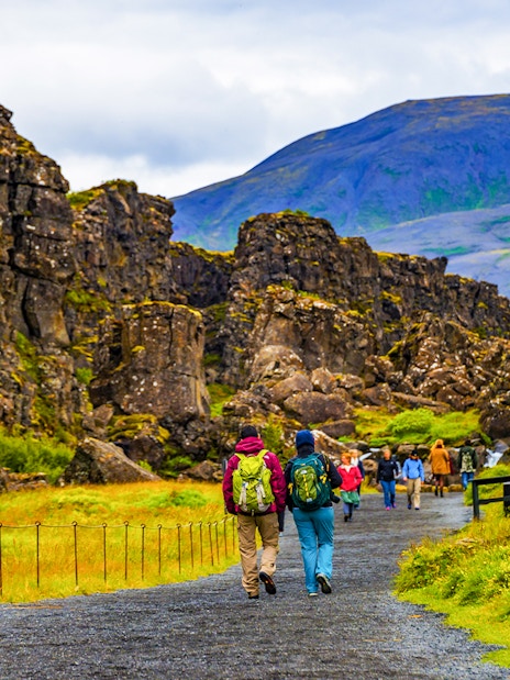 Tour group walking through Thingvellir National Park's rocky landscape on Reykjavik's Golden Circle tour.