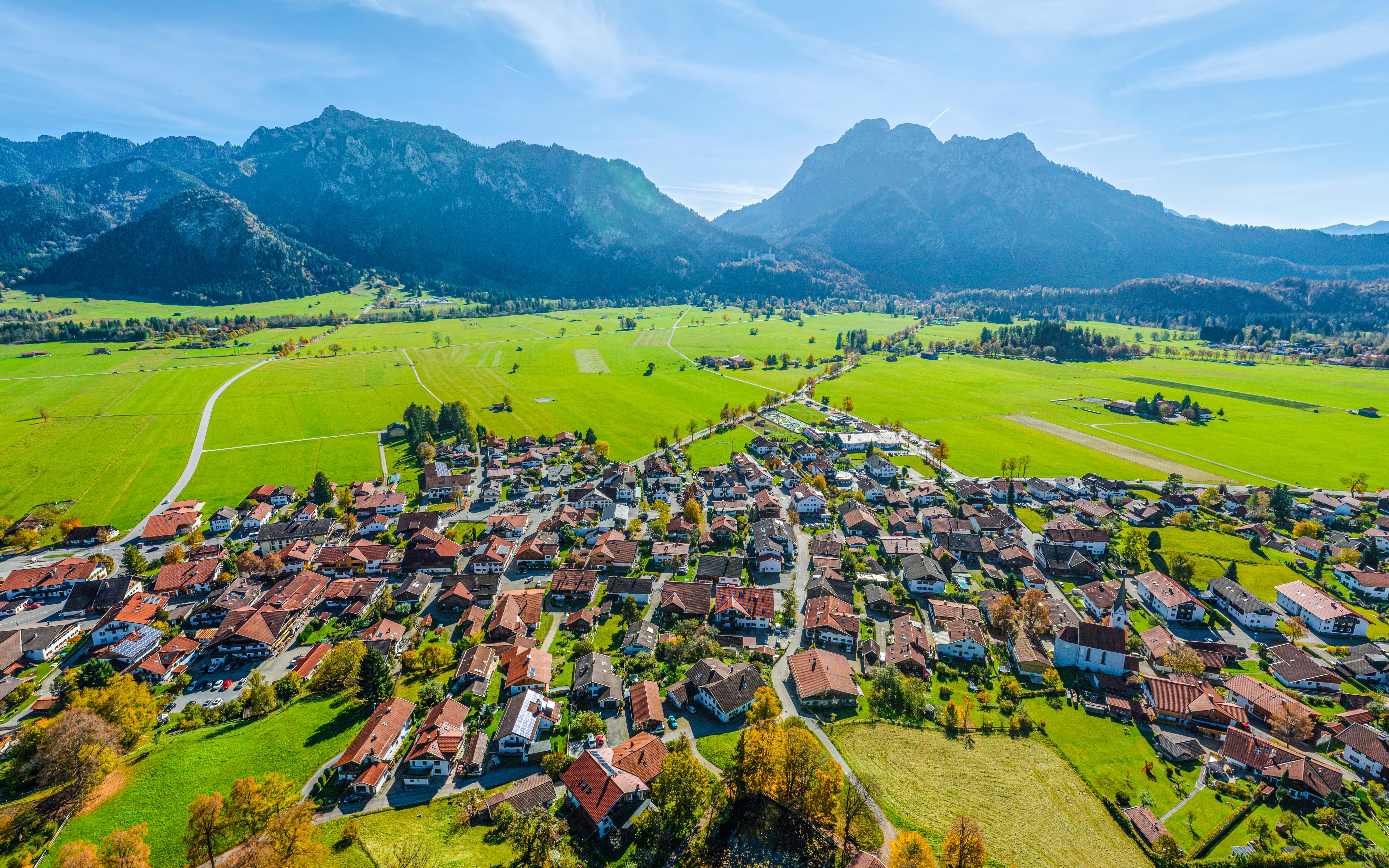 Aerial view of Schwangau Village with lush green fields and mountains in the background.