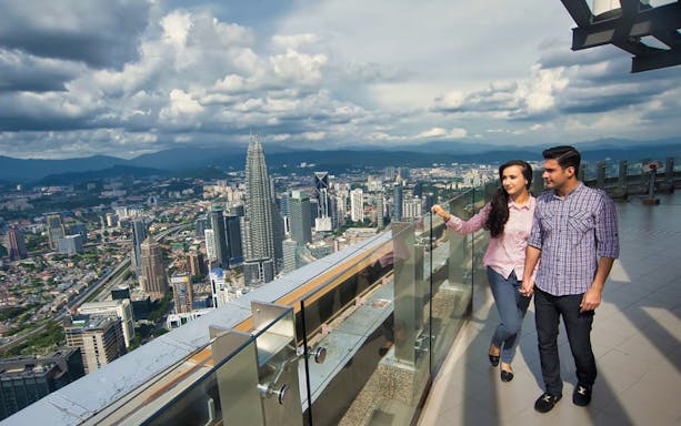 Couple enjoying city view from KL Tower observation deck.