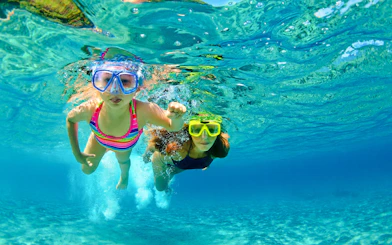 Mother and child snorkeling in clear blue water.