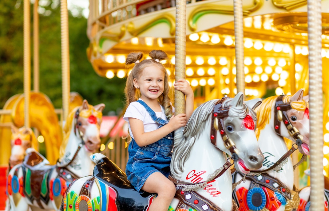 Child riding a carousel horse at an amusement park in Paris, France.