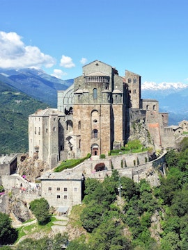 Sacra di San Michele monastery on a hilltop with mountains in the background, Italy.