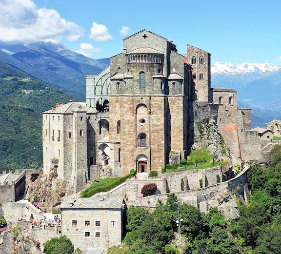 Sacra di San Michele monastery on a hilltop with mountains in the background, Italy.
