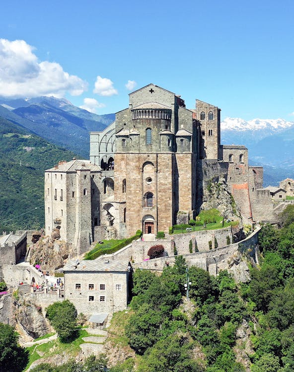 Sacra di San Michele monastery on a hilltop with mountains in the background, Italy.