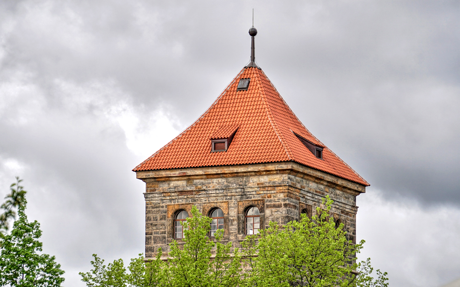 New Mill Water Tower with red roof in Prague, surrounded by trees.