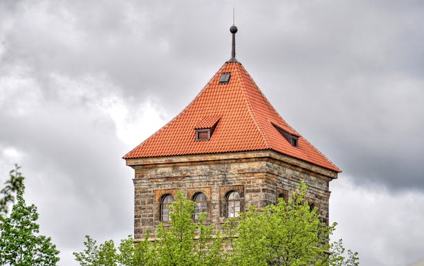 New Mill Water Tower with red roof in Prague, surrounded by trees.