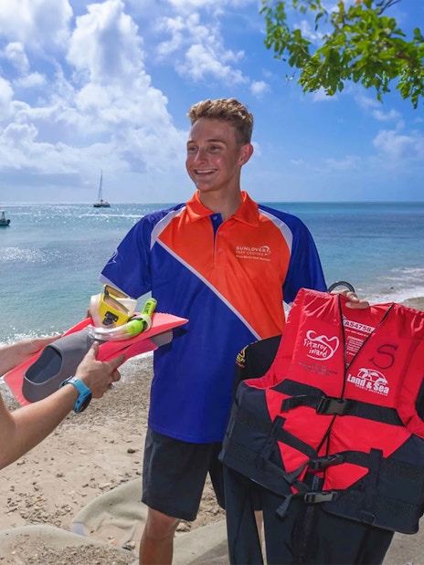 Tourists receiving snorkeling gear on Fitzroy Island beach, Great Barrier Reef.