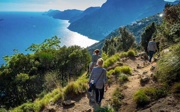 Hikers on Sentiero degli Dei trail overlooking Amalfi Coast, Italy.