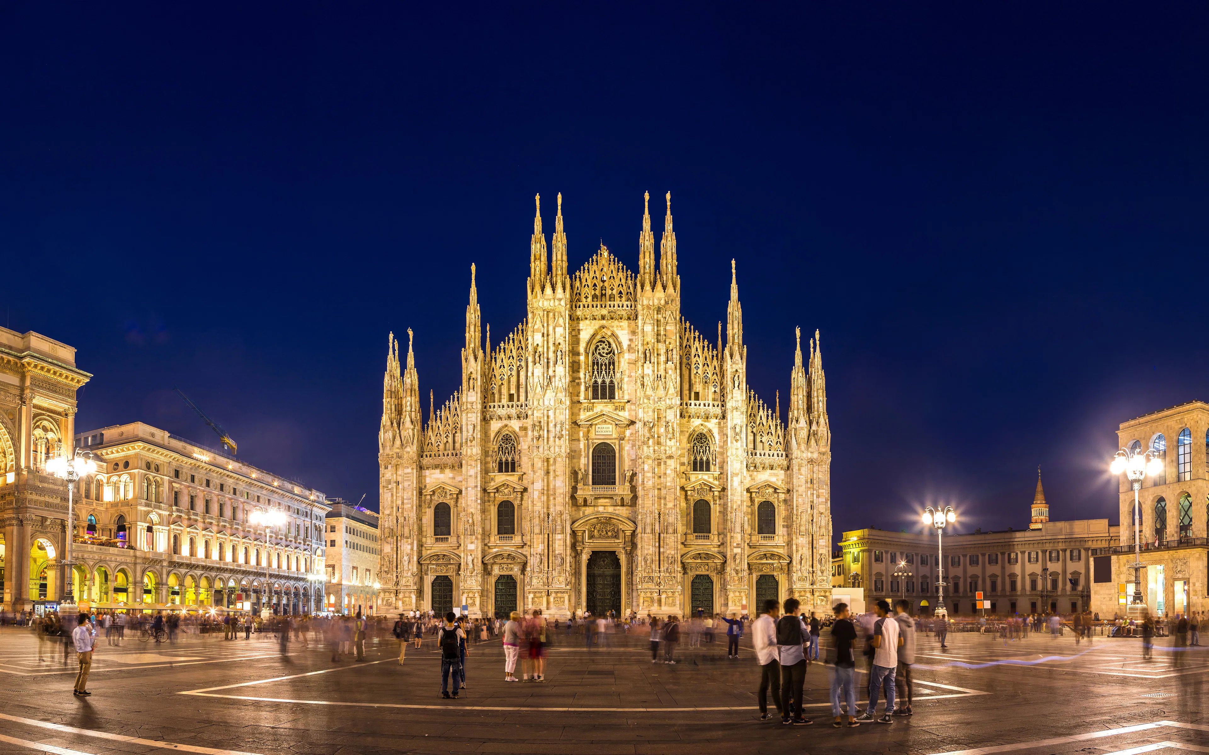 Duomo di Milano illuminated at night with people in the square, Milan, Italy.