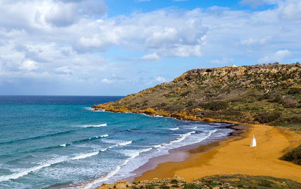 Gozo coastline with waves and sandy beach, part of the Gozo Jeep Tour.