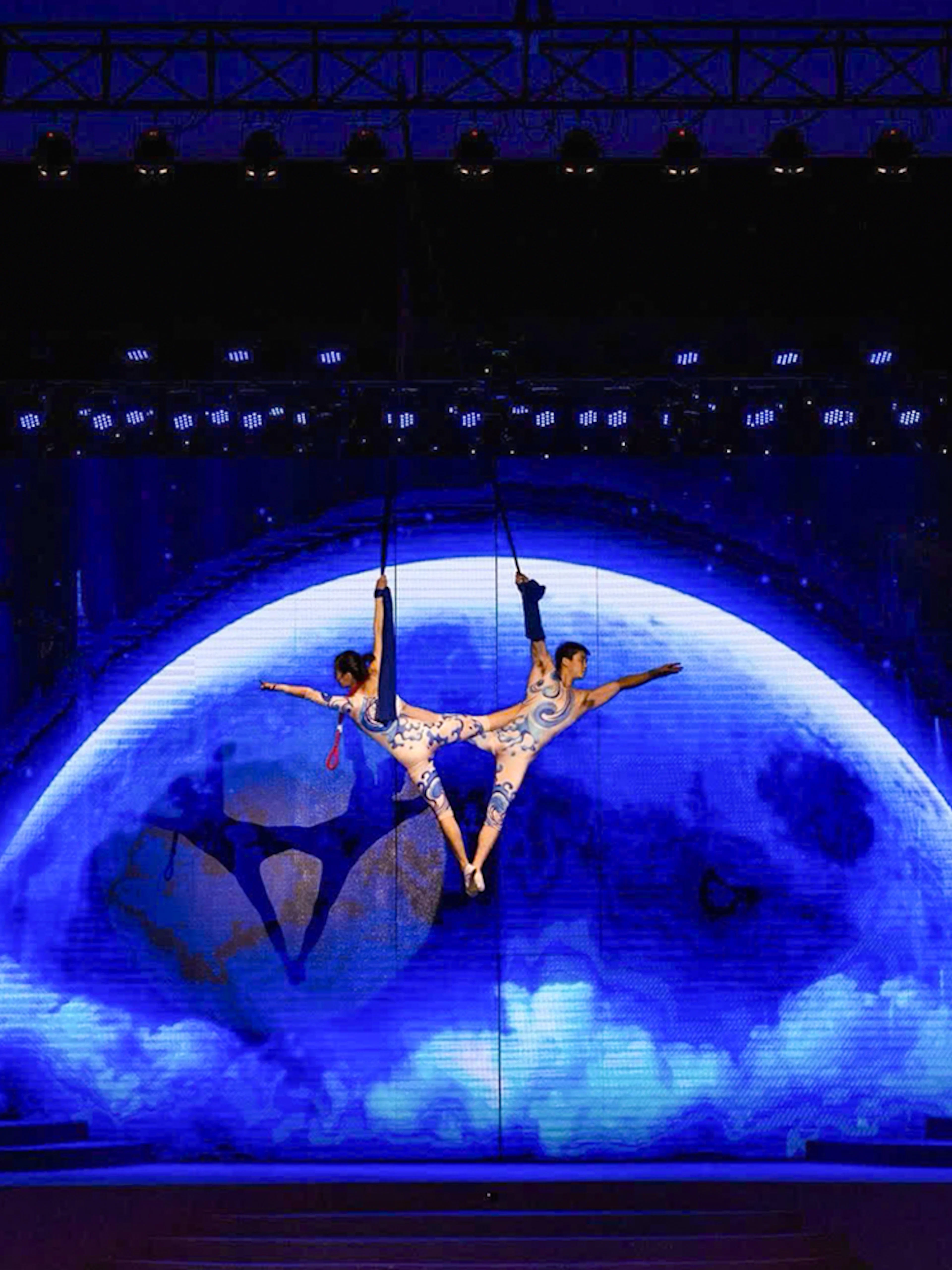 Acrobats performing aerial act against a moonlit backdrop at Charming Danang Show, Da Nang.