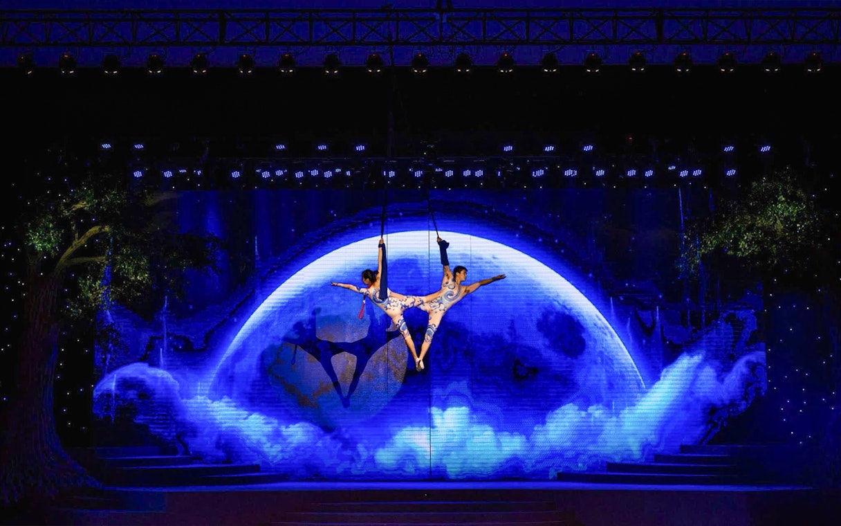 Acrobats performing aerial act against a moonlit backdrop at Charming Danang Show, Da Nang.