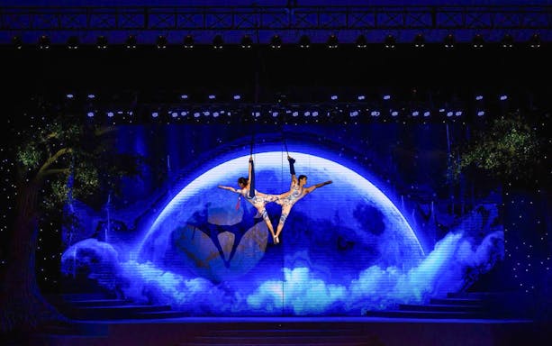 Acrobats performing aerial act against a moonlit backdrop at Charming Danang Show, Da Nang.
