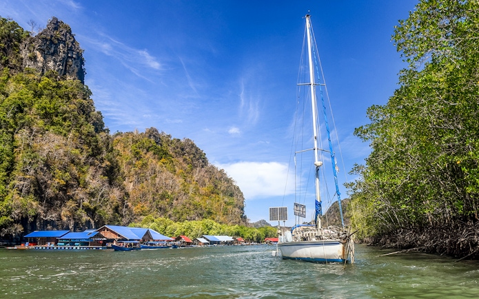 Sailboat near floating fish farm and mangroves on Andaman Sea, Langkawi Island tour.
