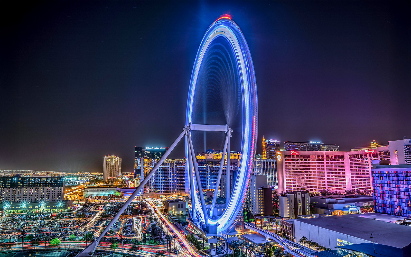 Las Vegas High Roller Observation Wheel illuminated at night with city skyline.