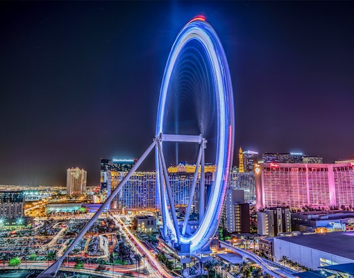 Las Vegas High Roller Observation Wheel illuminated at night with city skyline.