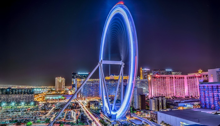 Las Vegas High Roller Observation Wheel illuminated at night with city skyline.