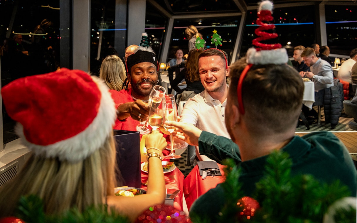 Guests toasting at Christmas dinner on Thames River cruise.
