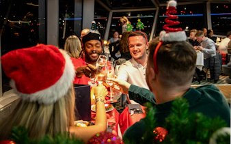 Guests toasting at Christmas dinner on Thames River cruise.