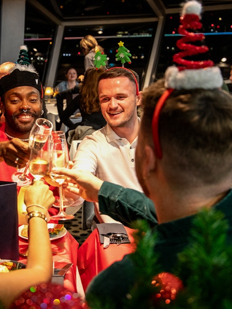 Guests toasting at Christmas dinner on Thames River cruise.