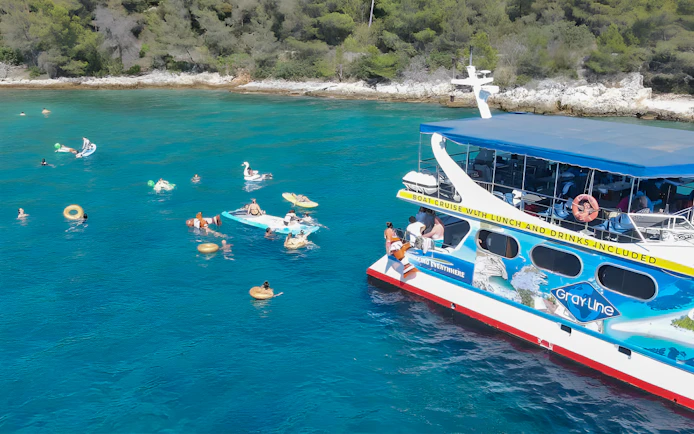Tourists swimming near a cruise boat in Split, Croatia, with inflatable floats and nearby islands.