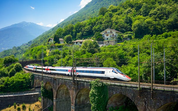 Train crossing a viaduct near Basel with lush green hills in the background.