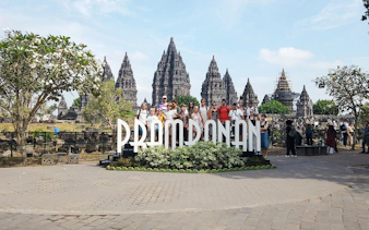 Tour group at Prambanan Temple complex, Indonesia, with ancient stone structures in the background.