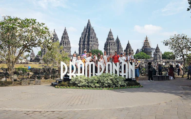 Tour group at Prambanan Temple complex, Indonesia, with ancient stone structures in the background.