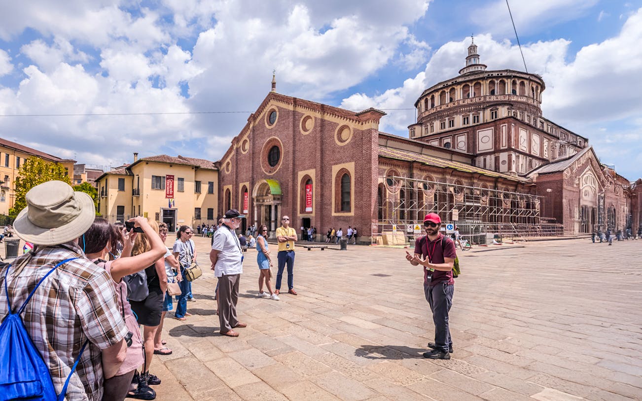 Tourists on a guided walking tour in front of the historic Duomo di Milano in Milan.