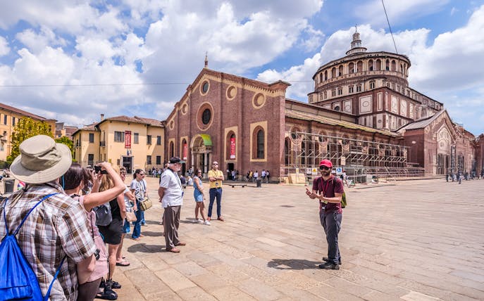 Tourists on a guided walking tour in front of the historic Duomo di Milano in Milan.