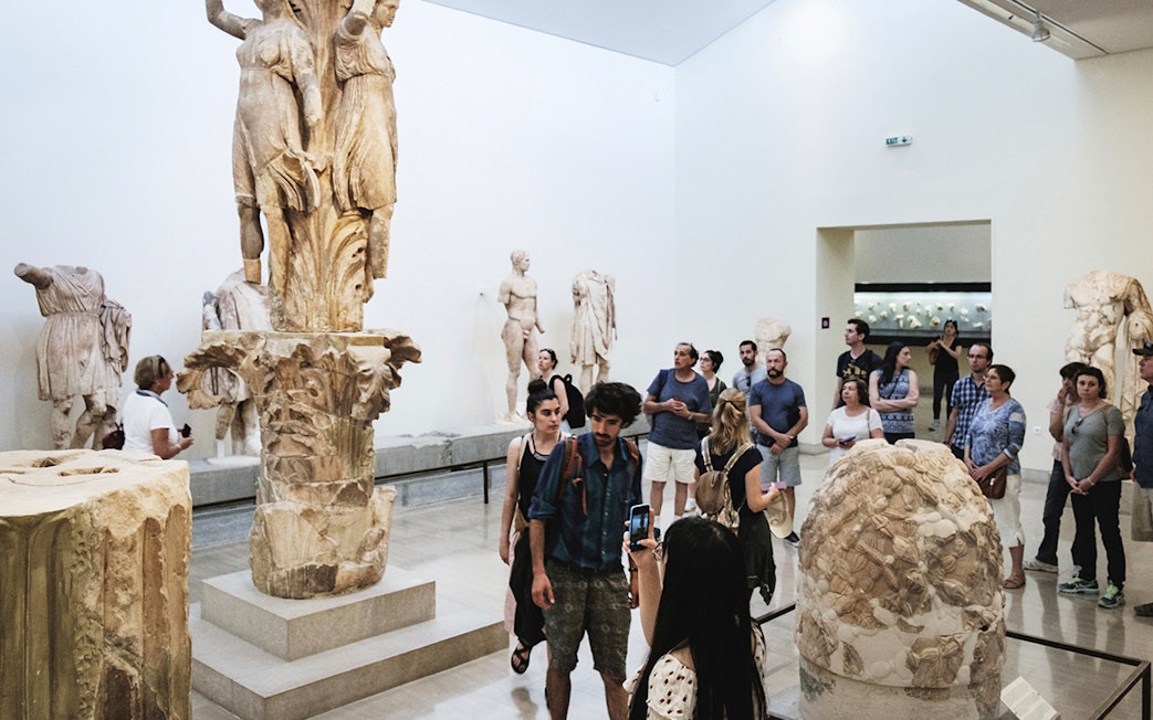 Visitors exploring sculptures at Delphi Archaeological Museum, Greece.