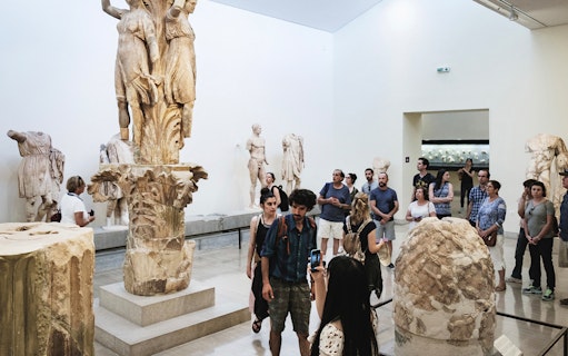 Visitors exploring sculptures at Delphi Archaeological Museum, Greece.