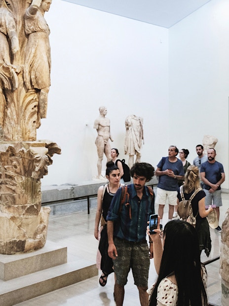 Visitors exploring sculptures at Delphi Archaeological Museum, Greece.