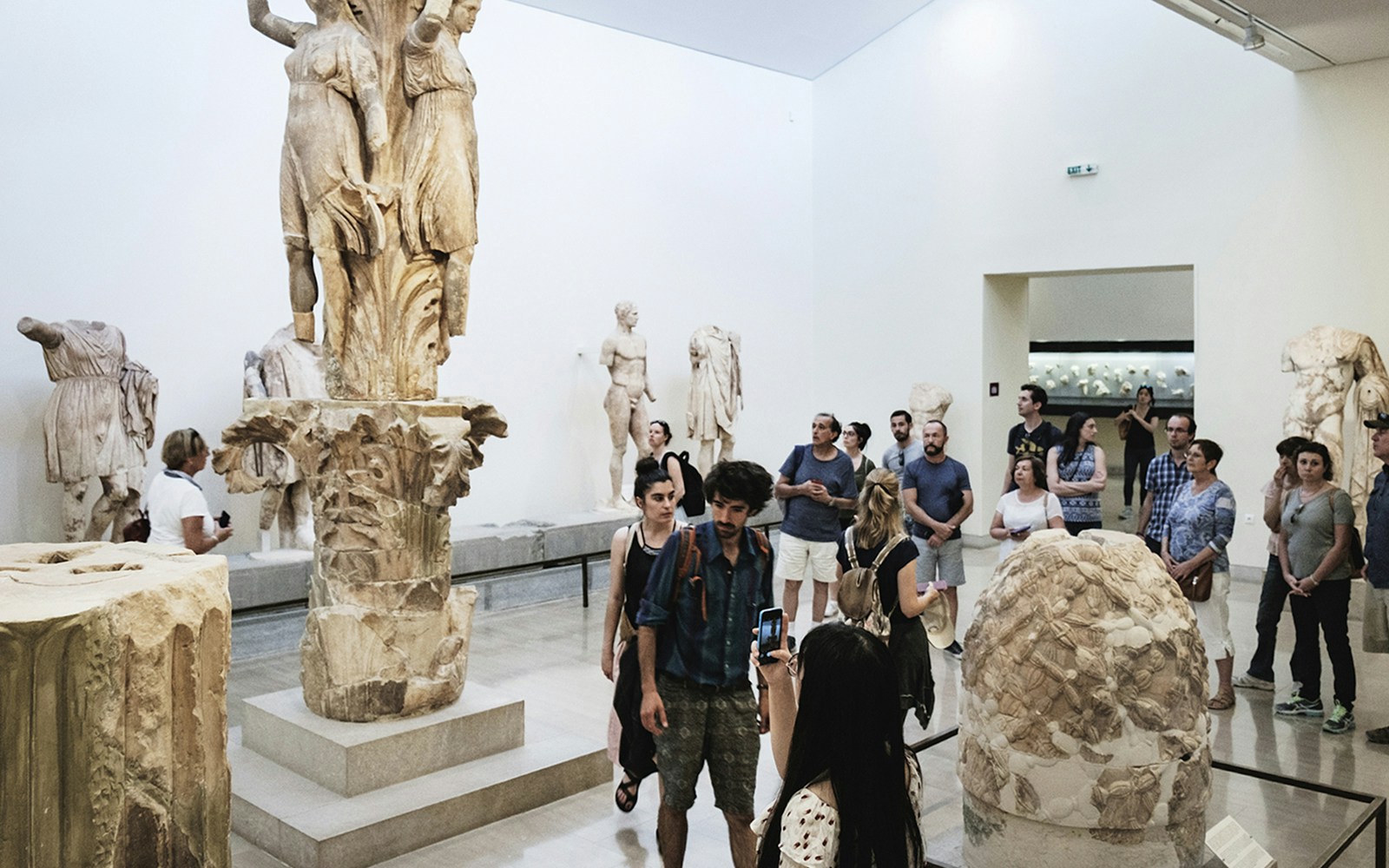 Visitors exploring sculptures at Delphi Archaeological Museum, Greece.