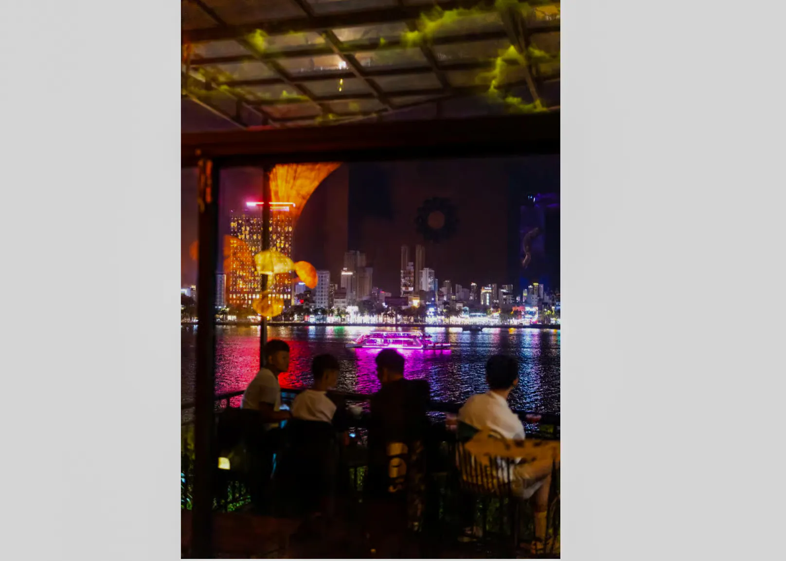 Night view of Da Nang skyline from a riverside café during a walking tour.
