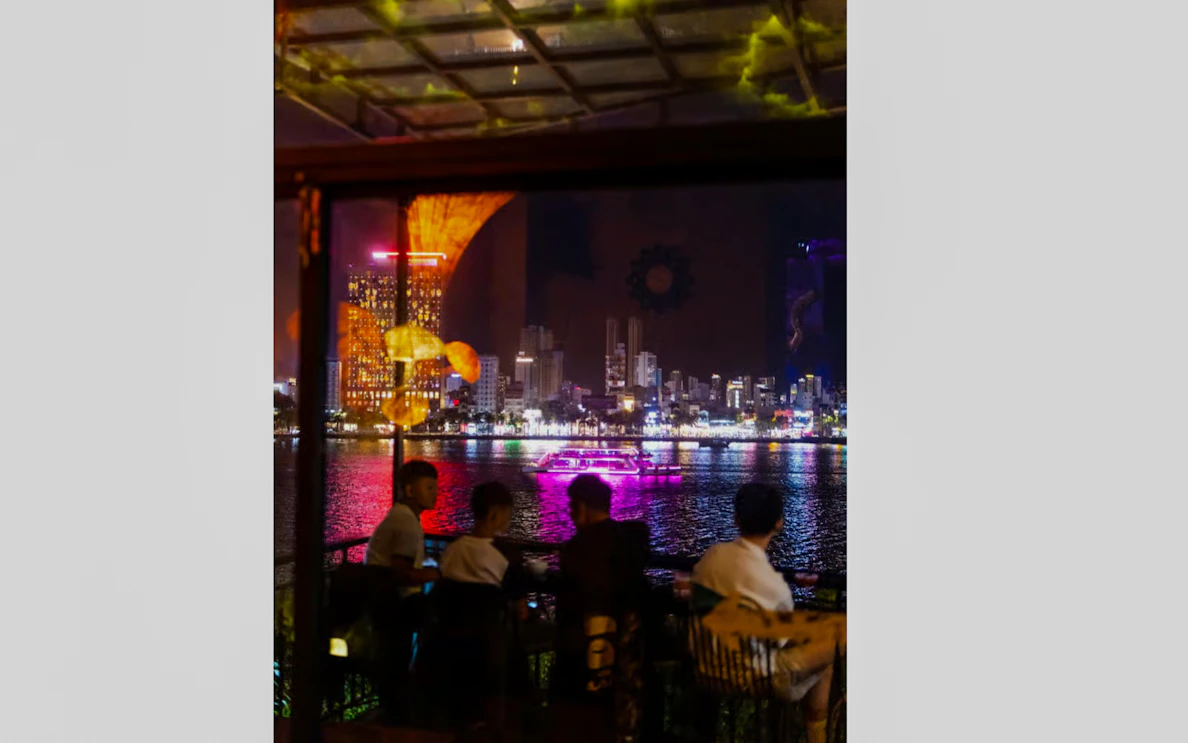 Night view of Da Nang skyline from a riverside café during a walking tour.