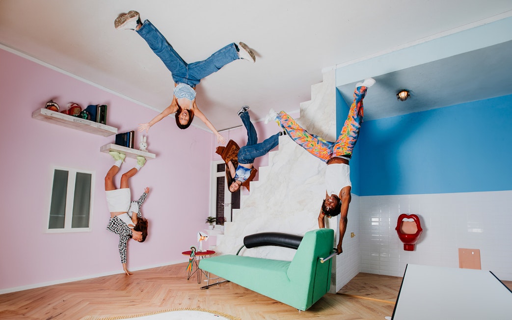 Visitors exploring the Upside Down Amsterdam exhibit with inverted furniture and decor.
