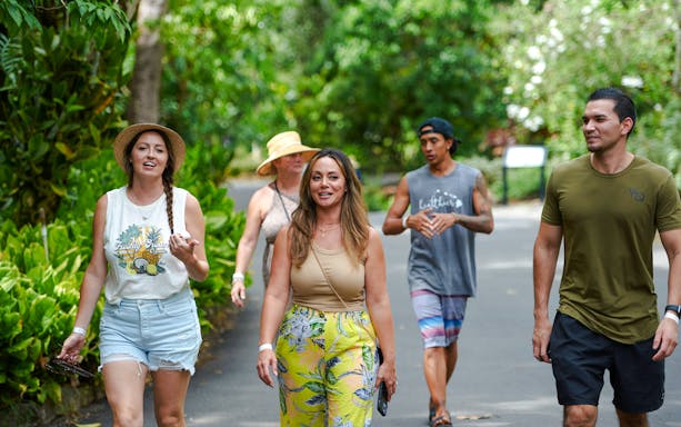 Five people walking on a paved path surrounded by lush greenery in Oahu, Hawaii.