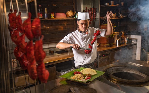 Chef preparing tandoori chicken skewers for Ulu Ulu Indian Buffet Dinner at Night Safari.