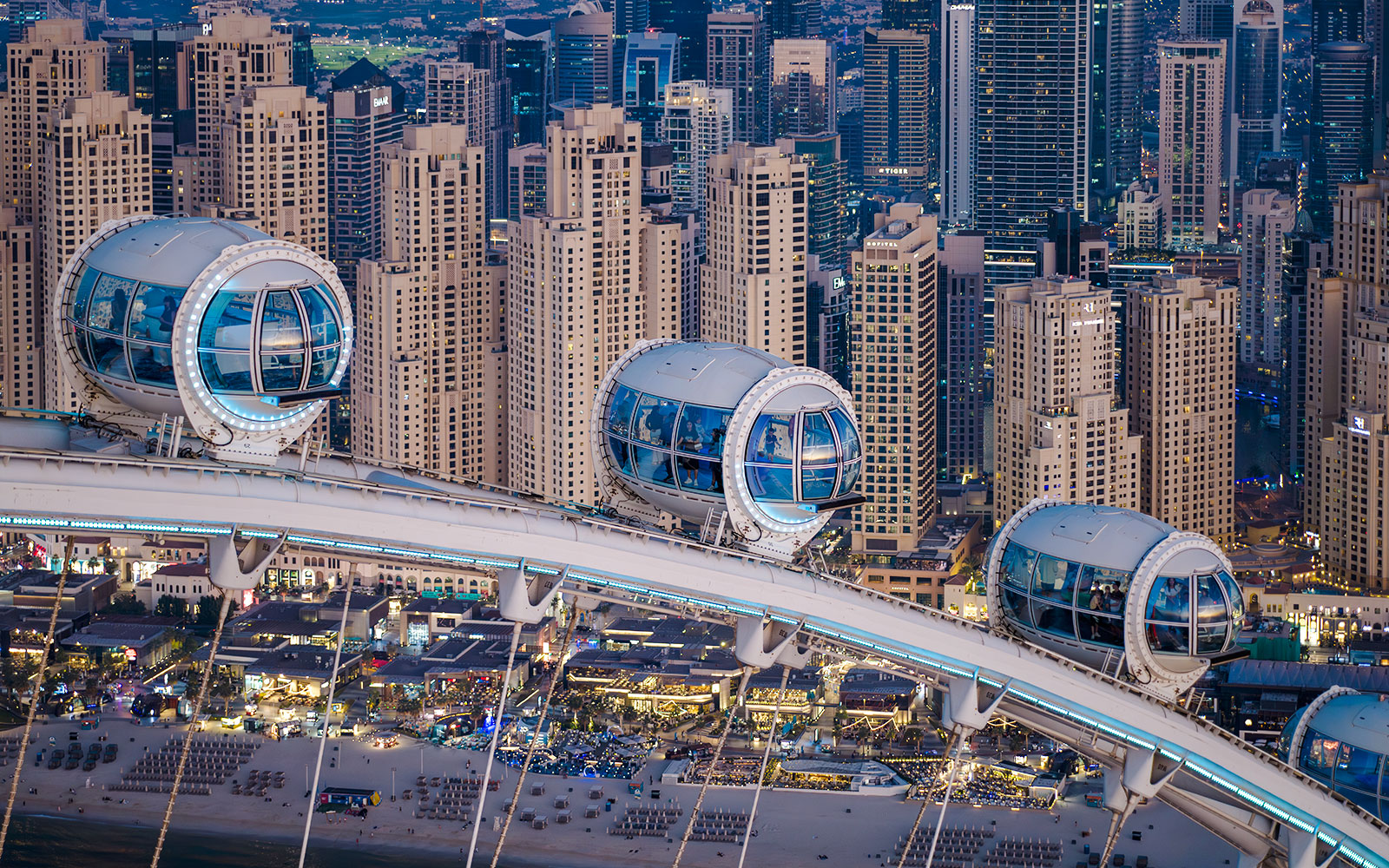 Ain Dubai pods overlooking Dubai skyline and beach.