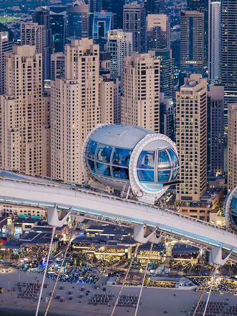 Ain Dubai pods overlooking Dubai skyline and beach.