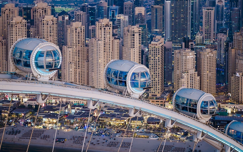 Ain Dubai pods overlooking Dubai skyline and beach.