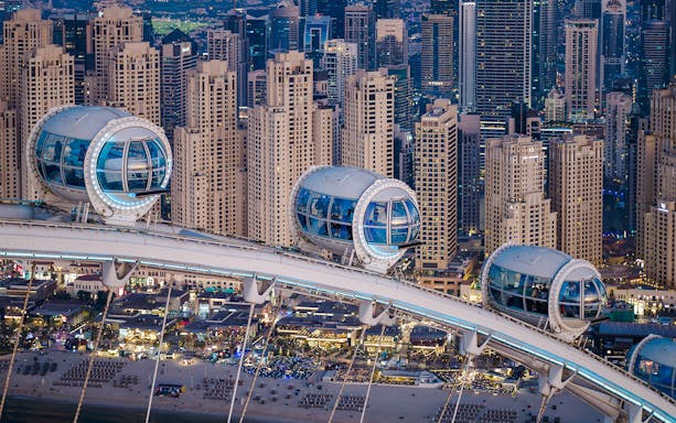 Ain Dubai pods overlooking Dubai skyline and beach.