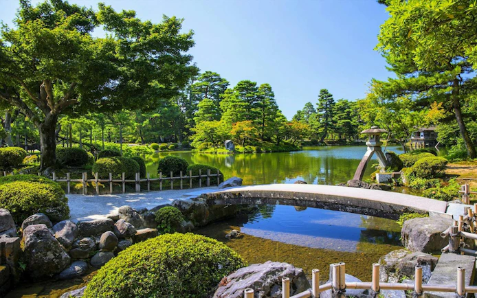 Serene garden with a stone bridge and pond in Shirakawa-go, Japan.
