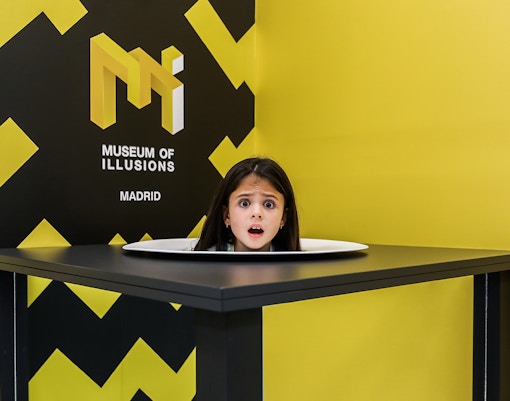 Visitors exploring head on a platter exhibit at the Museum of Illusions, Madrid.