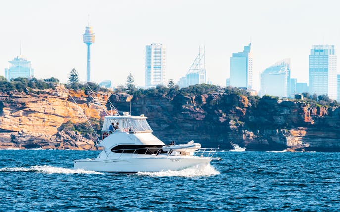Luxury yacht on Sydney Harbour with city skyline in background.
