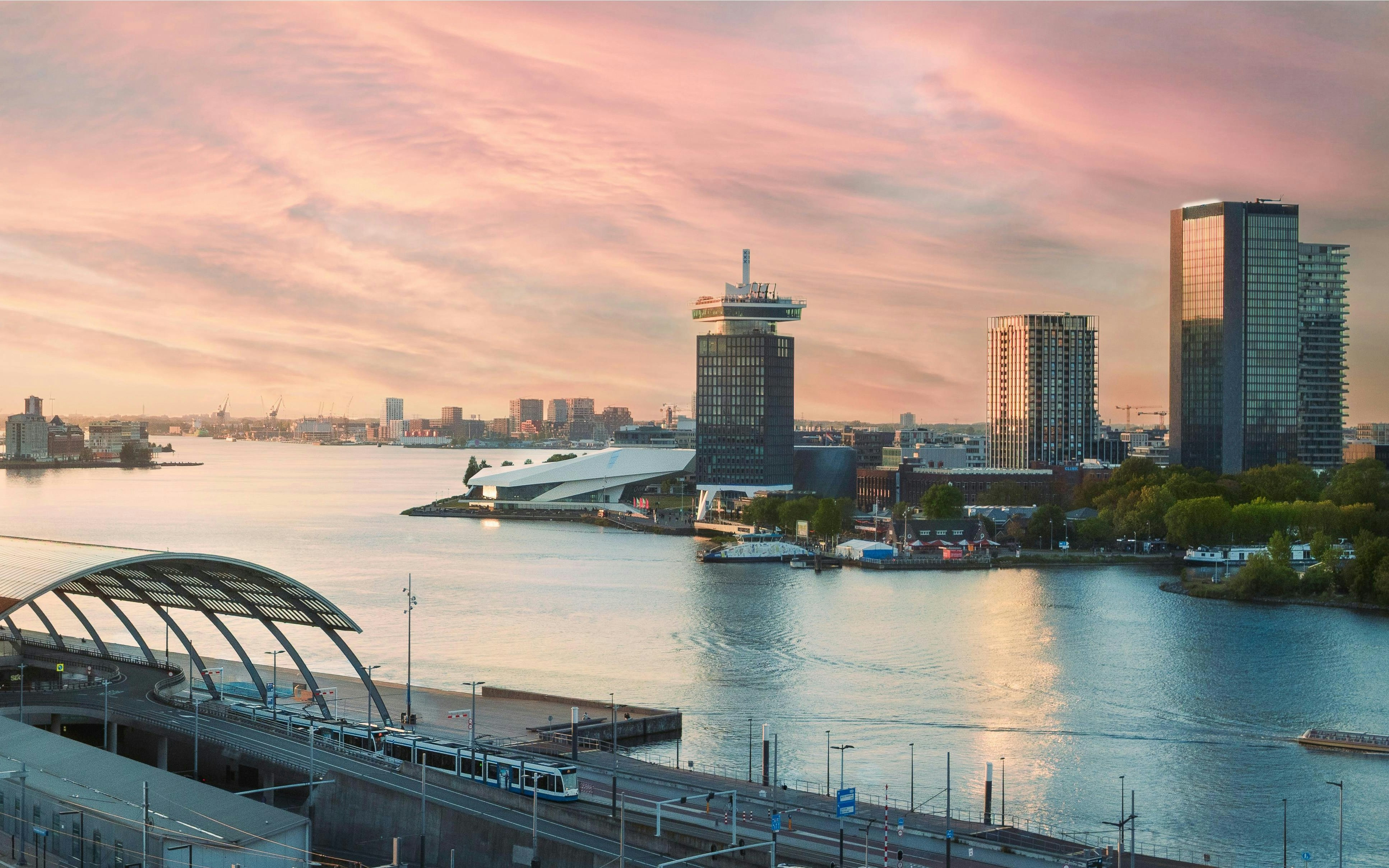 Panoramic view of Amsterdam skyline with A'dam Lookout Tower and Eye Film Museum at sunset.