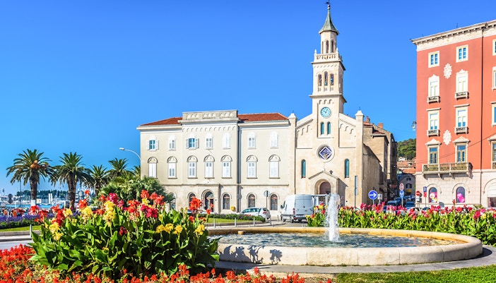 St. Francis Church in Split with a fountain and colorful flowers in the foreground.