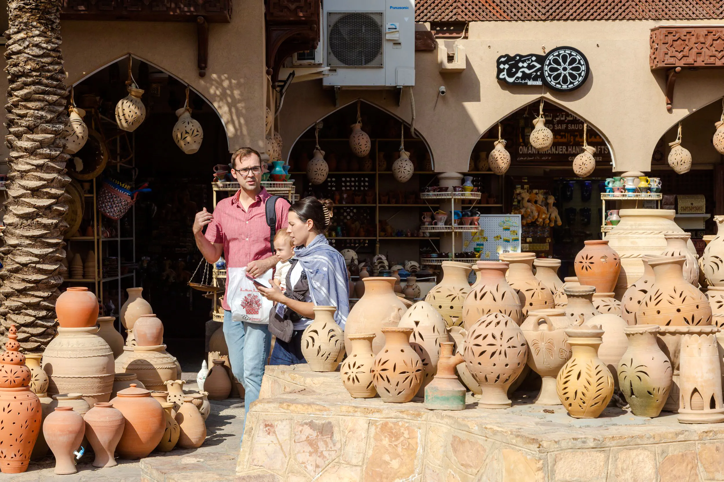 Nizwa pottery market with tourists exploring traditional clay pots, Oman.